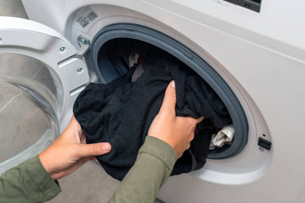 istock Young woman putting laundry in a washing machine 1434726939