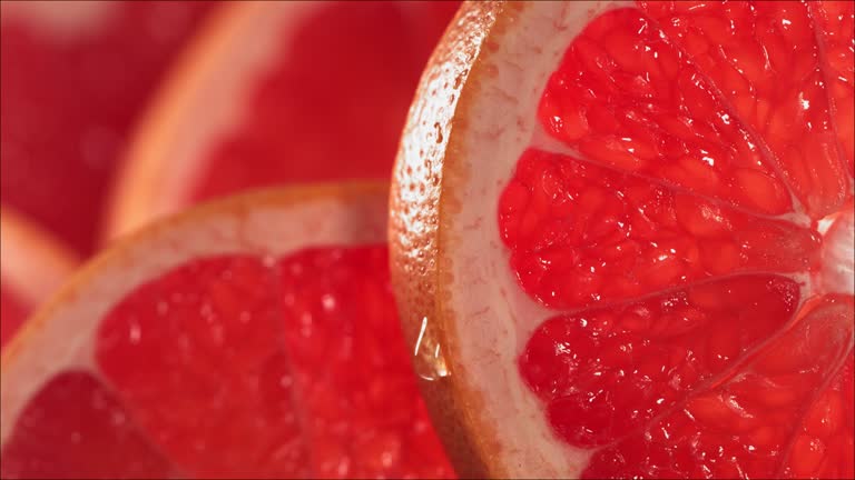 Drop of Water flows down the surface of a ripe juicy Grapefruit slice. Slow Motion 4K