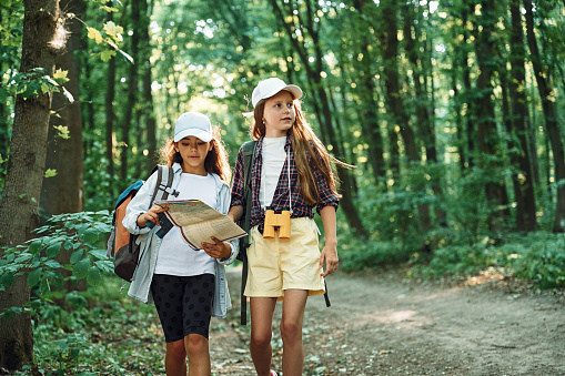 Using the map. Two girls is in the forest having a leisure activity, discovering new places.