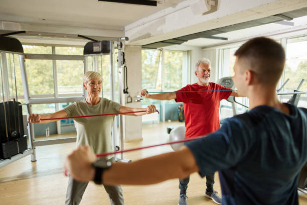 istock Senior couple exercising with personal trainer using resistance band 1434729389