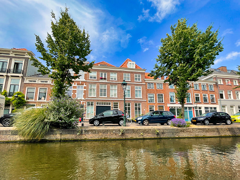 The Hague, Netherlands - June 19 2022: elegant historic dutch houses along a typical canal with a vibrant blue sky