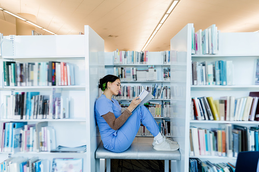 The young adult female medical student finds a quiet spot in the university library to study for her upcoming test.