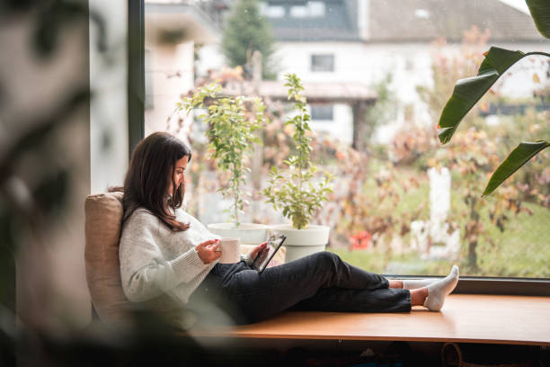 istock Young Female Relaxing On A Cozy Autumn Day, Reading A Book On A Digital Tablet 1434731734