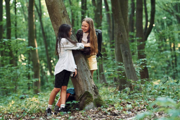 Standing and looking at each other. Two girls is in the forest having a leisure activity, discovering new places.