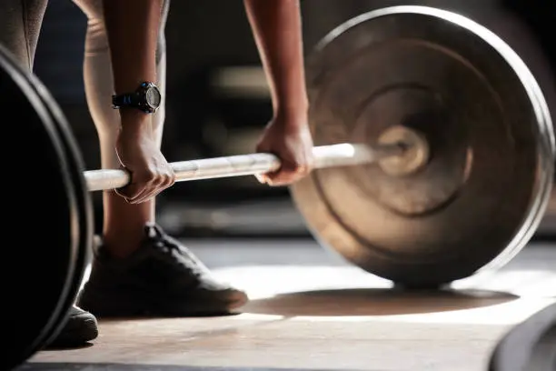 Photo of Barbell deadlift hands, strong fitness and power of black woman, athlete and bodybuilder in gym, sports workout and exercise. Closeup floor start, healthy muscle training and heavy challenge lifting