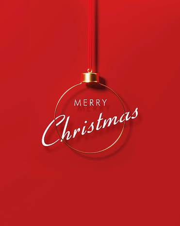 Merry Christmas message sitting behind gold colored bauble on red background. Christmas and festivity concept. Horizontal composition with copy space.