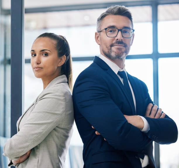 partnership, braccia incrociate e lavoro di squadra con due uomini d'affari in piedi insieme nell'edificio degli uffici aziendali. successo, motivazione e visione con i dipendenti in azienda di innovazione o gestione - leadership business women senior adult foto e immagini stock