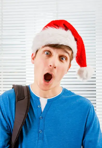 Surprised Young Man in Santa Hat on the Jalousie Background