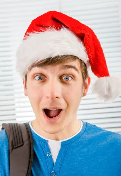 Surprised Young Man in Santa Hat on the Jalousie Background