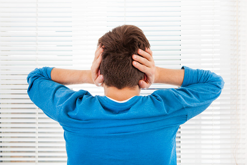 Rear View of a Man Covering his Ears from a Noise in the Room