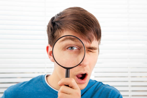 young man with a magnifying-glass - snooper imagens e fotografias de stock