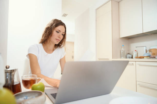 istock Woman is typing on laptop keyboard at kitchen table 1434739295