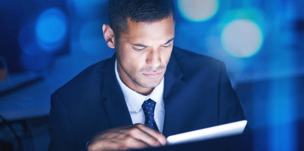 istock Businessman with digital tablet overtime for data research in a corporate office at night. Male entrepreneur and executive worker using technology to communicate and network with online app or email 1434740389