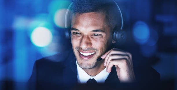 telemarketing customer support, consultant and help man on an online phone consultation at night. happy internet call center employee working on contact us digital web crm consulting in the dark - asking on the phone call center customer service representative imagens e fotografias de stock