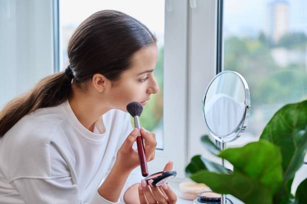 istock Young female with mirror doing morning daytime makeup, at home on windowsill 1434743504
