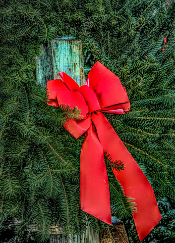 Christmas Wreath adorned by a bright red bow for sale