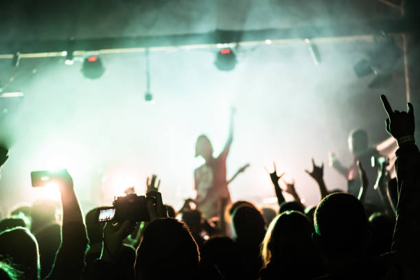 gente levantando las manos en el show de rock. público frente al escenario. concierto de rock en vivo. músicos de rock en el escenario - música punk fotografías e imágenes de stock