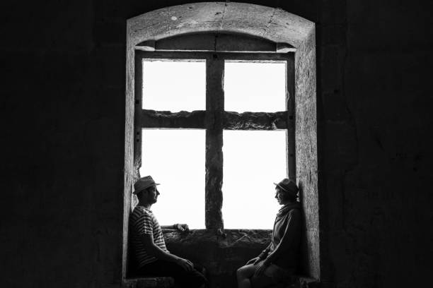 istock Couple in love sitting on a window bench and looking at each other. 1434752768
