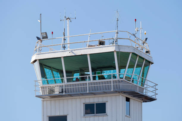 A close-up of an airport control tower with a radar dome on top, featuring a modern, geometric design.
