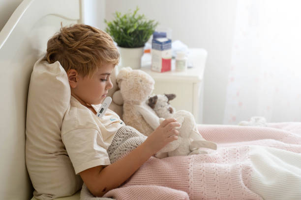 sick child in bed playing with his ill toy hare, measure body temperature with electronic thermometer. role playing, child playing doctor with plush toy. children cold and flu, coronavirus illness concept. - russian influenza epidemic virus flu virus imagens e fotografias de stock