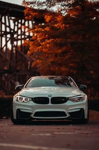 Tuscaloosa, United States – October 10, 2022: Front view of a modern white BMW M4 on the street during an autumn sunset. Luxury sports car