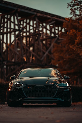 Tuscaloo, United States – October 10, 2022: Front view of a modern black Audi RS5 on the street during an autumn sunset. Luxury sports car