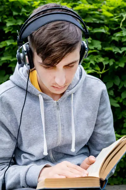 Young Man in a Headphones with a Books in the Summer Park