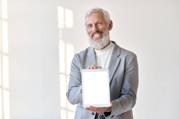 istock Smiling older business man showing tablet mockup screen isolated on white. 1434763183