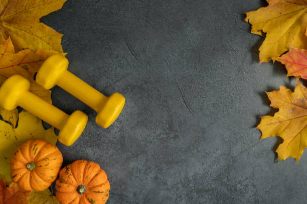 istock Autumn flat lay gym composition, with dumbbells, pumpkins on fall leaves and copy space. 1434763368