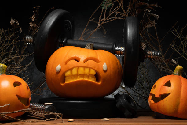 istock Halloween gym concept with carved pumpkin lifting dumbbells. 1434763539