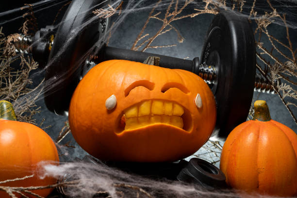 istock Halloween gym concept with carved pumpkin lifting dumbbells. 1434763554