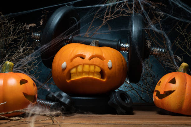 istock Halloween gym concept with carved pumpkin lifting dumbbells. 1434763563