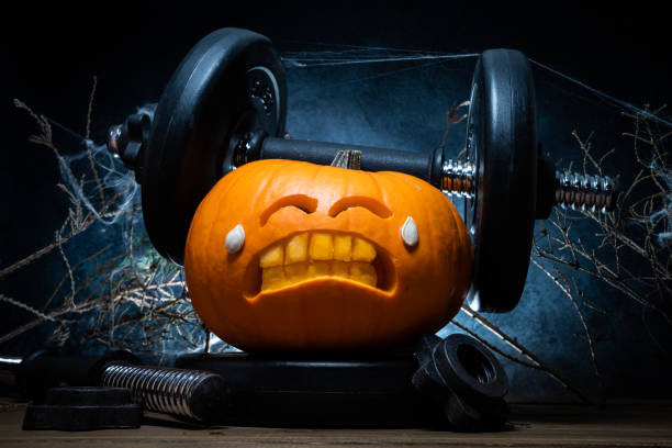 istock Halloween gym concept with carved pumpkin lifting dumbbells. 1434763568