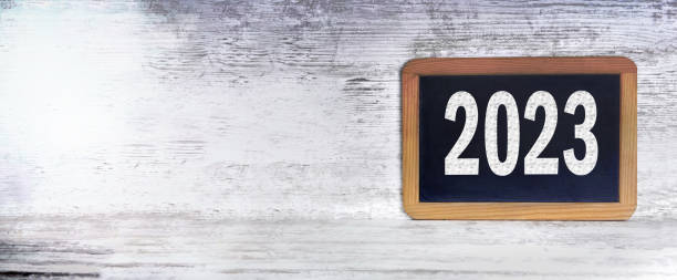 istock 2023 written on black slate on a white wooden background in panoramic view and large copy space onthe left 1434767782