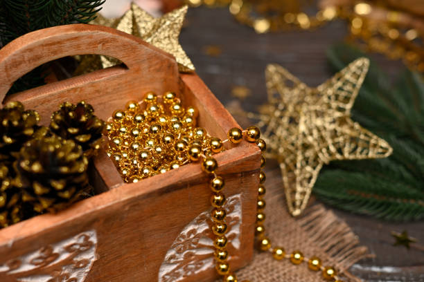 Set of thing useful for Christmas Tree decoration: fir branches, pine cones,  golden glittered stars, Christmas Tree beads, etc. in a rural box with wood carving ornament