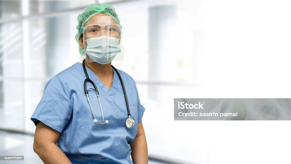 Asian doctor wearing face shield and PPE suit new normal to check patient protect safety infection Covid-19 Coronavirus outbreak at quarantine nursing hospital ward. Nurse Stock Photo