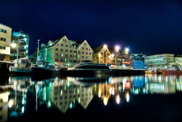 Scenic view of buildings reflected on the calm lake in Tromso harbor at night Tromso, Norway – December 10, 2005: A scenic view of buildings reflected on the calm lake in Tromso harbor at night finnmark stock pictures, royalty-free photos & images