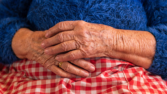 Close up elderly hands of a widowed old woman. Caucasian 90s grandma sitting at home. Wrinkled hands of the grandmother