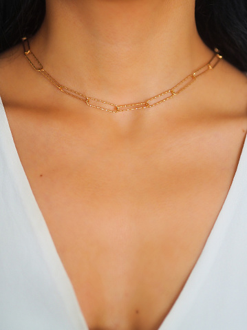 Silver bijouterie chain on woman neck. Black background.