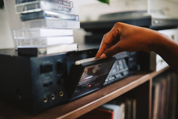 Young woman listening to music at her home, going through a collection of vinyl records and cassette tapes.