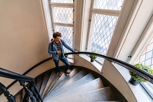 Handsome young man using smart phone while walking up the staircase, in Stockholm, Sweden.