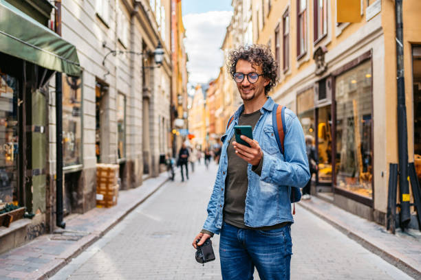 turista joven usando un mapa en un teléfono inteligente - tourist map men holding fotografías e imágenes de stock