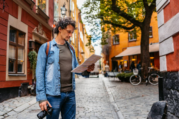 giovane turista che legge una mappa in città - tourist map men holding foto e immagini stock