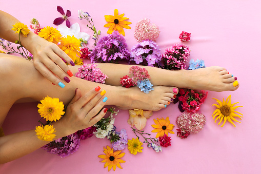 Multicolored manicure and pedicure on square shaped nails with different flowers.