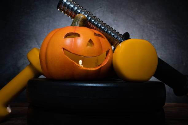 istock Halloween composition with ceramic pumpkin lantern, yellow gym dumbbell and barbell plates. 1434790362