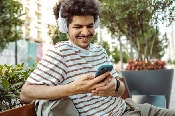 istock Young man relaxing on the bench and using a smart phone 1434791865