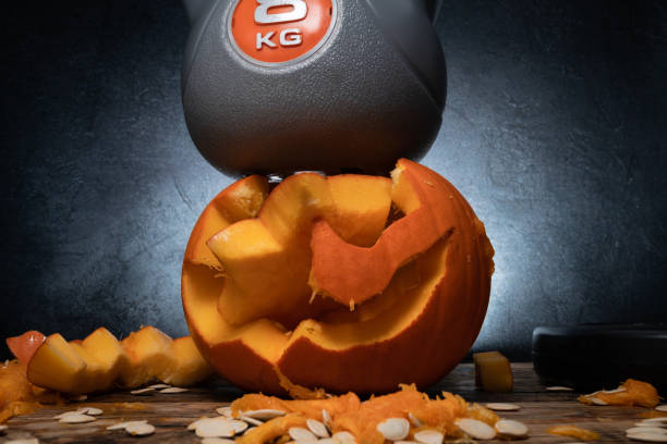 istock Heavy gym kettlebell crushing carved Halloween pumpkin. 1434791907