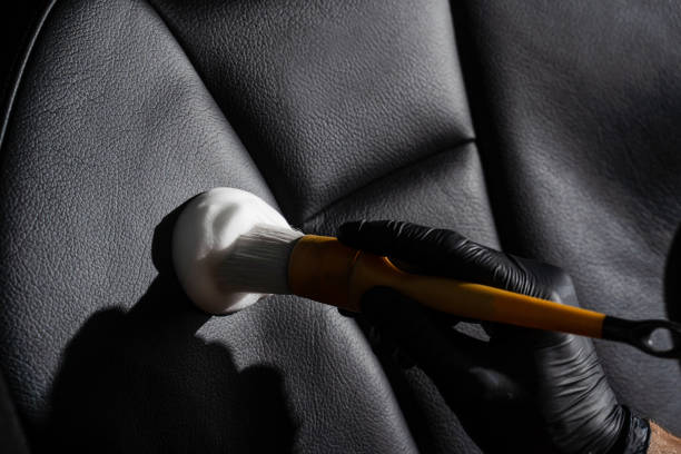 istock Process of foam and detergent cleaning leather seat using brush. Worker in auto cleaning service clean car inside. Car interior detailing. 1434795040