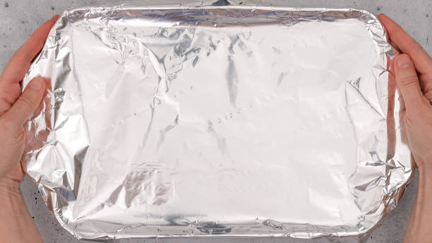 istock Baking dish covered with aluminum foil close up on the table, flat lay. Spinach lasagna recipe. 1434797375