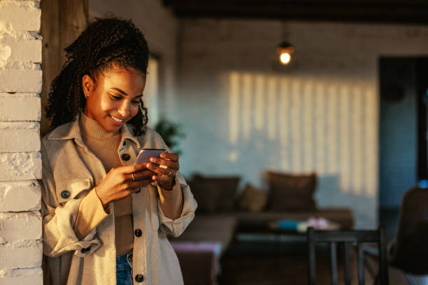 istock Cheerful woman using smartphone in apartment. 1434798018